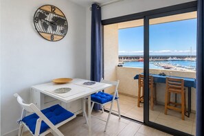 A balcony with a view of a marina, a white table with blue cushions, and a wall clock. - GuestReady - Charming Beachfront Apartment (La Restinga)
