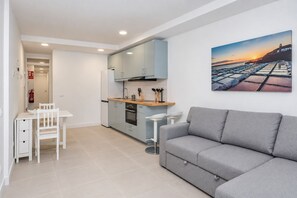 Une cuisine moderne avec des meubles de couleur bleu clair, un plan de travail en bois et un coin repas comprenant une table et des chaises blanches.