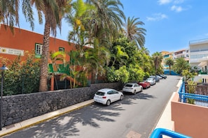 Une rue bordée de voitures garées, de palmiers et d’immeubles sur lesquels on peut lire l’inscription « Hacienda San Jose ».