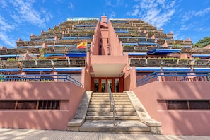 L’entrée d’un hôtel, avec un escalier central menant à un bâtiment doté de nombreux balcons.
