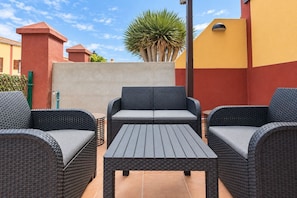 Une terrasse dotée de meubles en osier, notamment deux canapés et une table.