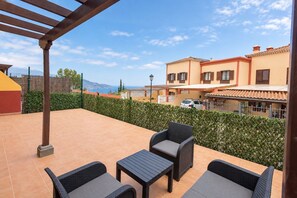 Eine Terrasse mit Gartenmöbeln, einer Pergola und Blick auf ein Gebäude mit einem Ziegeldach.