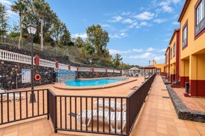Una piscina con una pared de piedra, una cerca blanca y un camino empedrado.