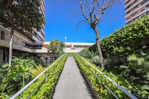 A pathway flanked by greenery and buildings, leading towards a clear blue sky. - GuestReady - Amazing retreat in Torremolinos (Torremolinos)
