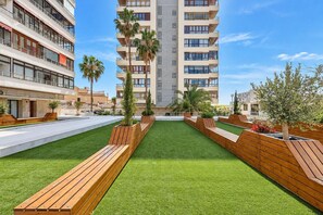 A modern building with multiple balconies, a rooftop garden with wooden planters and benches, and a clear sky. - GuestReady - Amazing retreat in Torremolinos (Torremolinos)