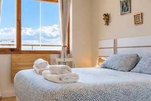 Ein Schlafzimmer mit Bett, Handtüchern, einem Sessel und Blick zum Himmel.
