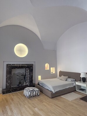 A modern bedroom with a bed, bedside table, and a fireplace. - Vaulted ceilings just renovated loft apartment Tarquinia old town (Tarquinia)