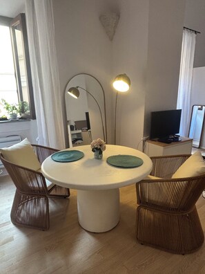 Ein runder Esstisch mit zwei Stühlen, einer Blumenvase und zwei Stehlampen.