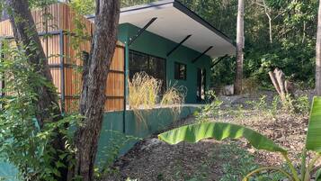 Un bâtiment moderne à la façade verdoyante, entouré d’une végétation luxuriante et d’arbres.