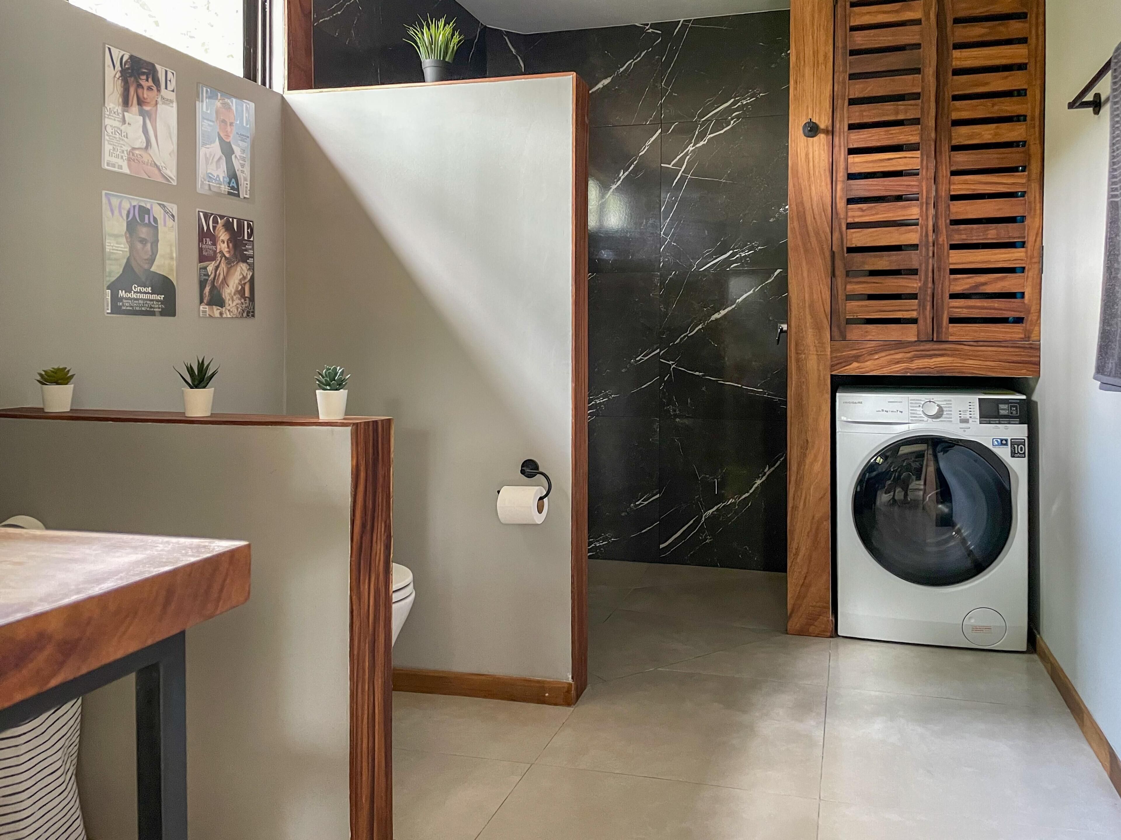 Un bagno compatto con un mobile bagno in legno, una lavatrice e un WC.