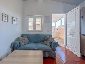 Ein Zimmer mit einer Couch, einer Tür und einem Fenster.