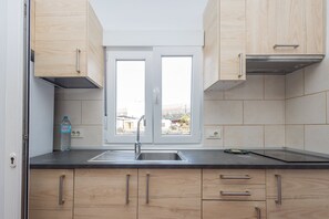 Eine Küche mit Holzausstattung, einer schwarzen Arbeitsplatte, einer Edelstahlspüle und einem Fenster mit Blick auf Gebäude.