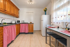Une cuisine dotée de meubles en bois, d’un four à micro-ondes, d’un réfrigérateur et d’un coin repas avec une table et des chaises.