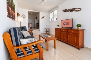 Un salon comprenant un canapé, un meuble en bois, un téléviseur et une table à manger.