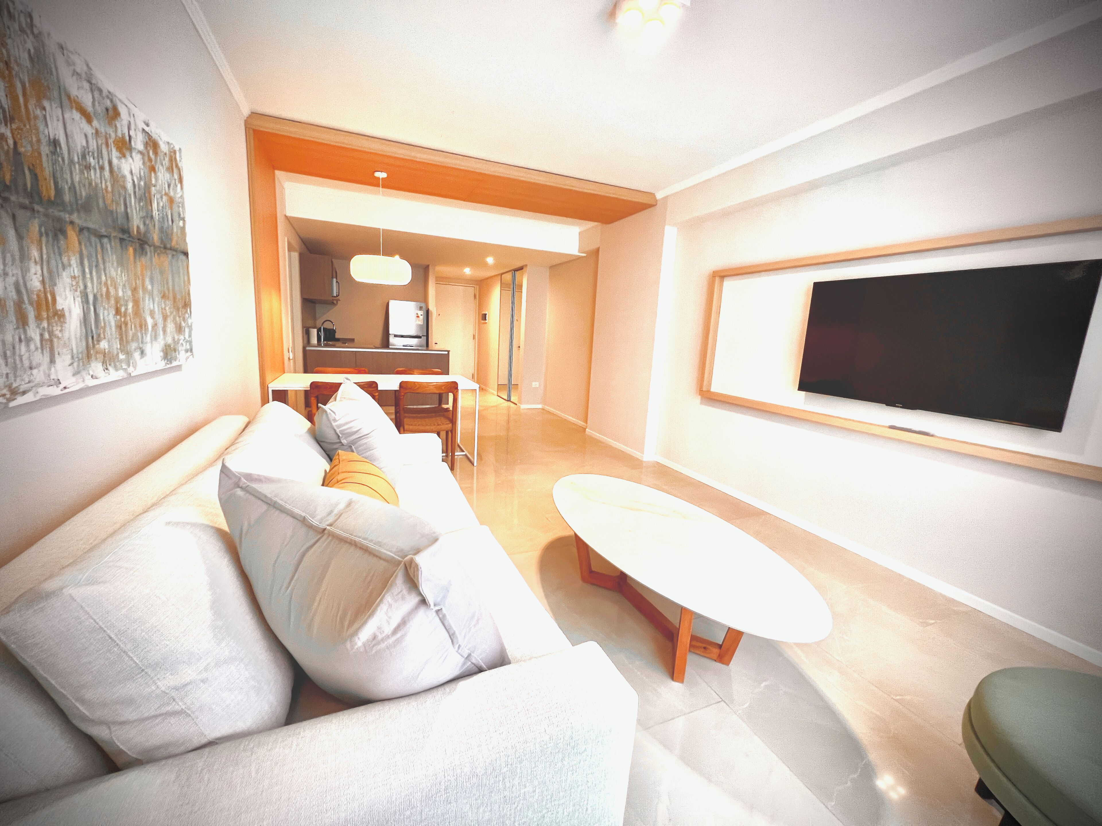 A modern living room with a sofa, a coffee table, and a TV mounted on the wall.