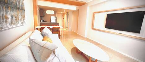 A modern living room with a sofa, a coffee table, and a TV mounted on the wall.