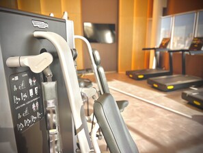 Uma academia com equipamentos de ginástica, incluindo esteira e bicicleta ergométrica.