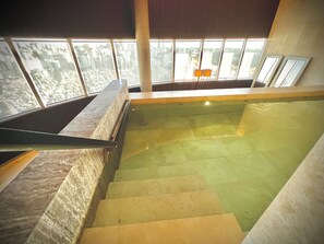 Ein moderner, überdachter Pool mit freiem Blick auf die Stadt durch große Fenster.