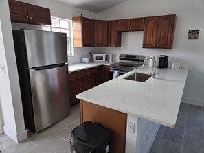 A modern kitchen with stainless steel appliances, wooden cabinets, a granite countertop, and a built-in oven. - Sleeps 24. Three houses on 1.2 acres of ocean front property. (Melbourne Beach)