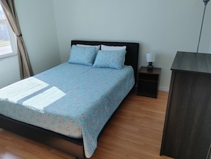 A bedroom with a bed, a nightstand, and a dresser.
