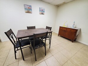 A dining area with a wooden table and chairs, a cabinet with decorative items, and two beach-themed paintings on the wall. - Sleeps 24. Three houses on 1.2 acres of ocean front property. (Melbourne Beach)