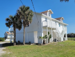 A two-story white house with a balcony, a front porch, and a staircase leading to the upper floor. - Sleeps 24. Three houses on 1.2 acres of ocean front property. (Melbourne Beach)
