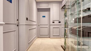 A hallway with double doors, a glass display case, and a sign indicating a room number. - VivimiHome-Luxury Suite: Acquamarina (Milan)