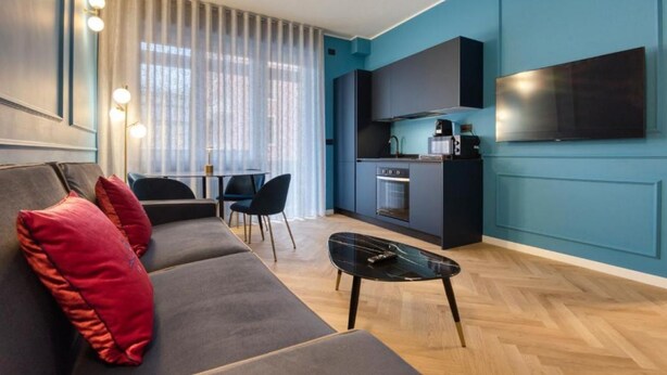 A modern living room with a sofa, a coffee table, and a dining area with chairs. - VivimiHome-Luxury Suite: Acquamarina (Milan)