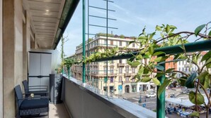 A balcony with a view of buildings, a chair, and a table. - VivimiHome-Luxury Suite: Acquamarina (Milan)