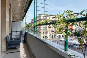 Ein Balkon mit Blick auf Gebäude, einem Stuhl und einem Tisch.