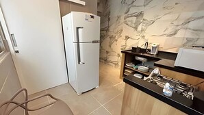 Una cocina compacta con un refrigerador blanco, un lavamanos y una encimera con varios objetos.