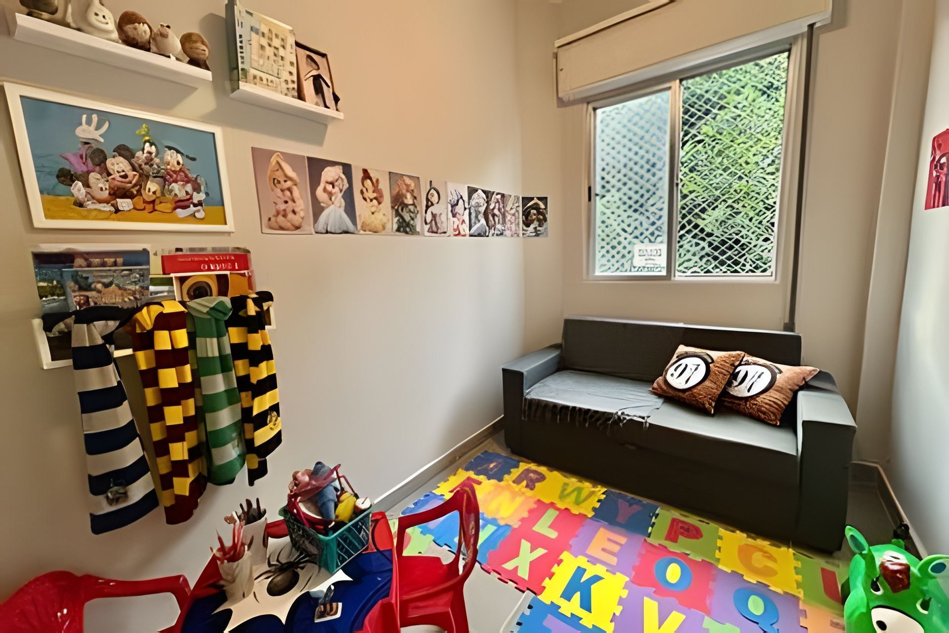 Un cuarto de juegos infantil con un sofá, alfombras de espuma con el abecedario y varios juguetes.