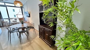Un comedor con una mesa redonda y sillas, un aparador de madera oscura y una planta verde grande.