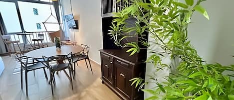 Un comedor con una mesa redonda y sillas, un aparador de madera oscura y una planta verde grande.