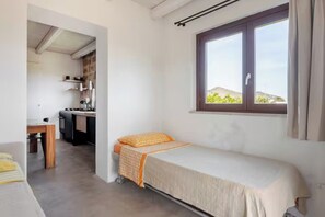 A compact room with a bed, a small desk, and a kitchenette.
