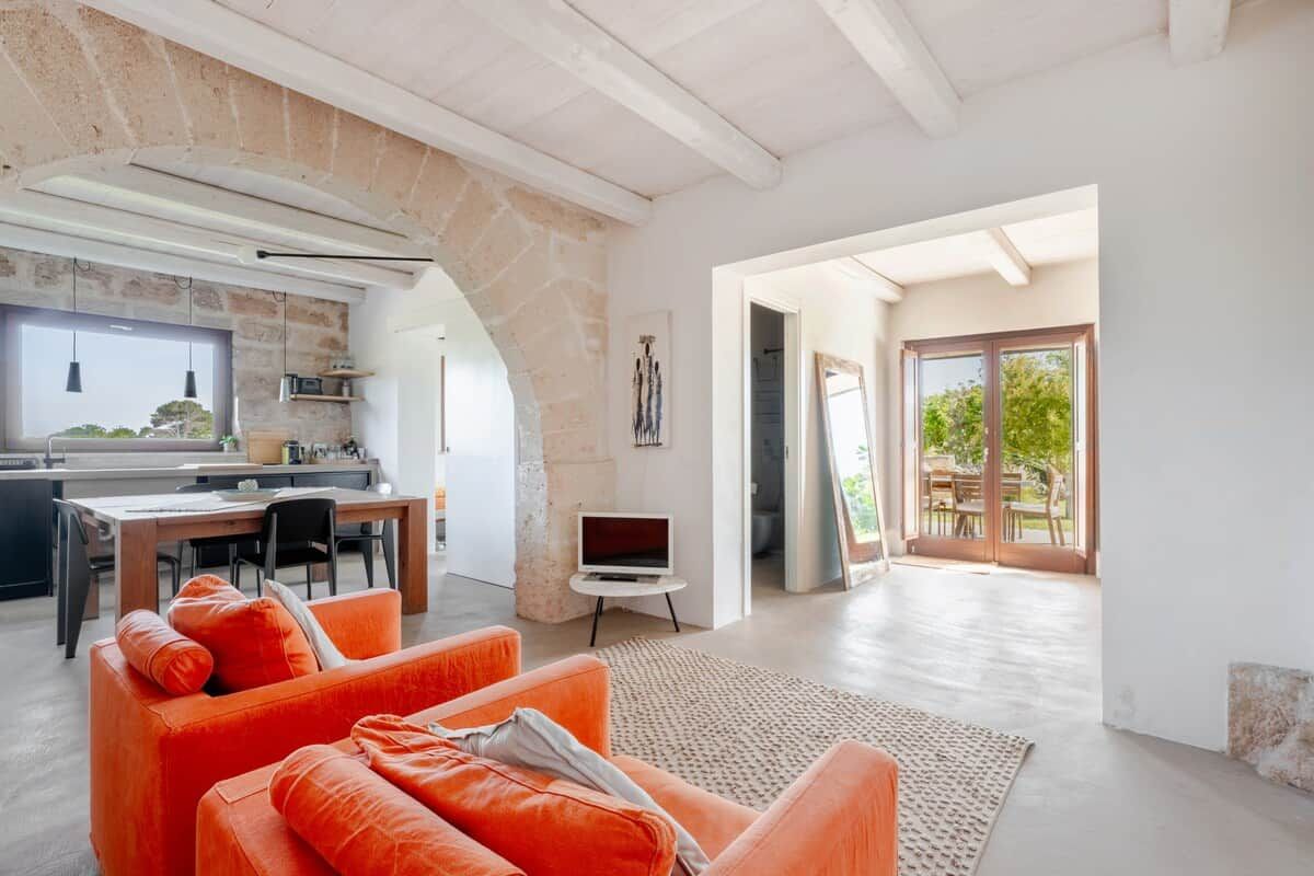 A modern living space with a stone archway, a dining area, and a view to an outdoor patio.