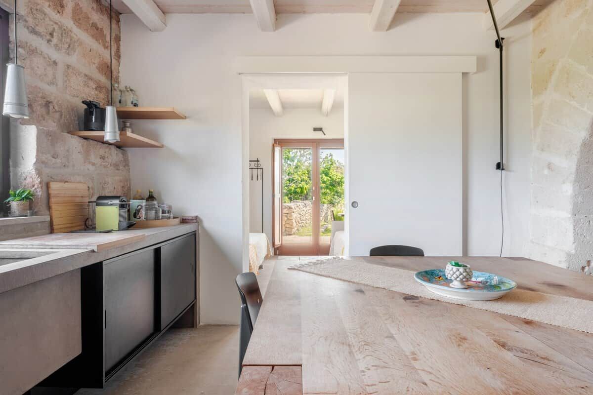 Une cuisine moderne avec une table en bois, des placards intégrés et une vue sur l’extérieur.