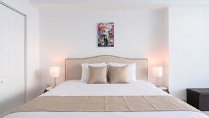Une chambre d’hôtel avec un grand lit, deux lampes de chevet et une œuvre d’art accrochée au mur.