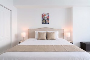 Ein Hotelzimmer mit einem großen Bett, zwei Nachttischlampen und einem an der Wand befestigten Kunstwerk.