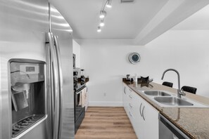 A modern kitchen with stainless steel appliances, a built-in oven, and a double sink. - 2 Penthouses Sleeps 14 · Brickell, Free Parking (Miami)