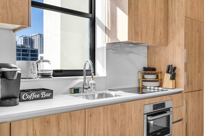 A modern kitchen with a coffee bar, a sink, a Bosch oven, and wooden cabinets. - 4BR/4BA 2-Unit Combo for 12 · Rooftop Pool + Views (Miami)