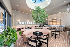 A modern lounge area with curved seating, a central tree, and a bar with shelves. - 4BR/4BA 2-Unit Combo for 12 · Rooftop Pool + Views (Miami)
