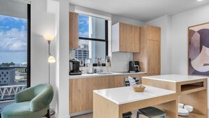 A modern kitchen with wooden cabinets, a white countertop, and a view of the city. - 4BR/4BA 2-Unit Combo for 12 · Rooftop Pool + Views (Miami)