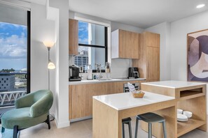 Eine moderne Küche mit Holzschränken, einer weißen Arbeitsplatte und Blick auf die Stadt.