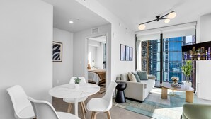 A modern living room with a dining area, large windows, and a city view. - 4BR/4BA 2-Unit Combo for 12 · Rooftop Pool + Views (Miami)