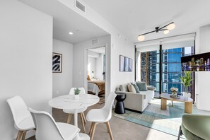 Ein modernes Wohnzimmer mit Essbereich, großen Fenstern und Blick auf die Stadt.