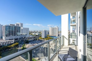 A balcony with a view of a cityscape, including modern buildings and a parking lot. - 4BR/4BA 2-Unit Combo for 12 · Rooftop Pool + Views (Miami)