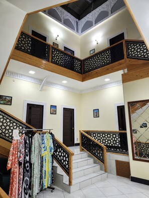 Un interior de varios niveles con una escalera, barandas de madera y paredes con diseño.