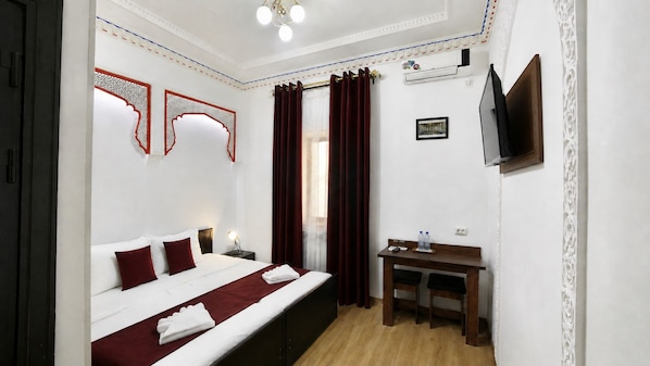 A hotel room with a bed, bedside table, desk, and a television. - RAY BOUTIQUE HOTEL (Bukhara)