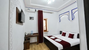 A hotel room with a bed, a desk, a radiator, and an air conditioning unit. - RAY BOUTIQUE HOTEL (Bukhara)